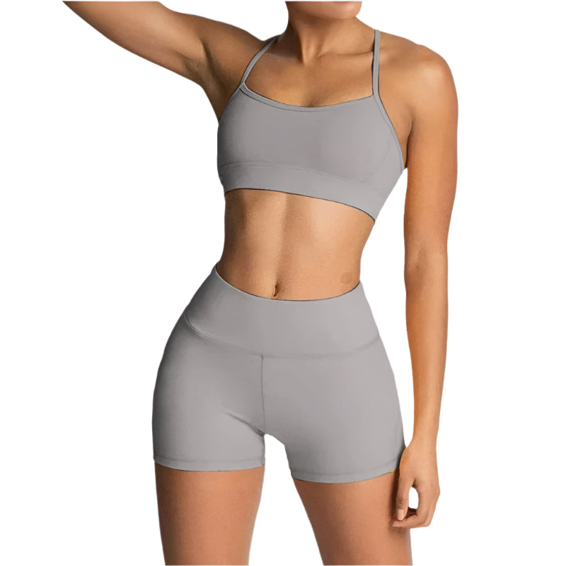 Person wearing a gray sports bra and shorts set on a light gray background