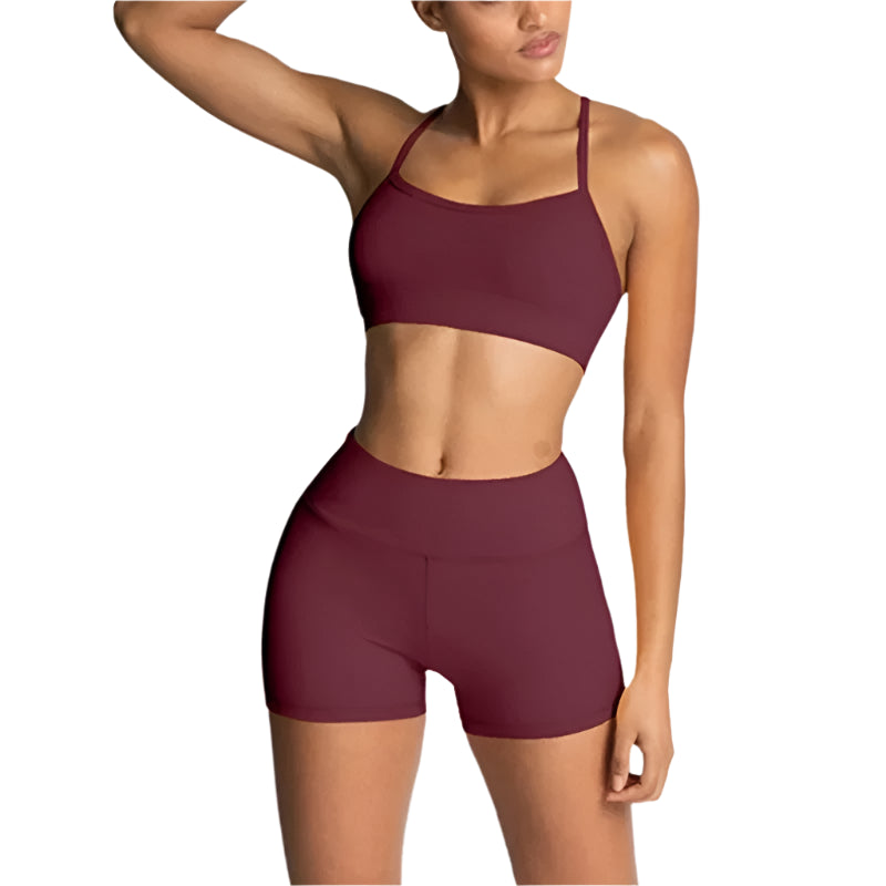 Woman wearing a maroon sports bra and shorts set on a light gray background