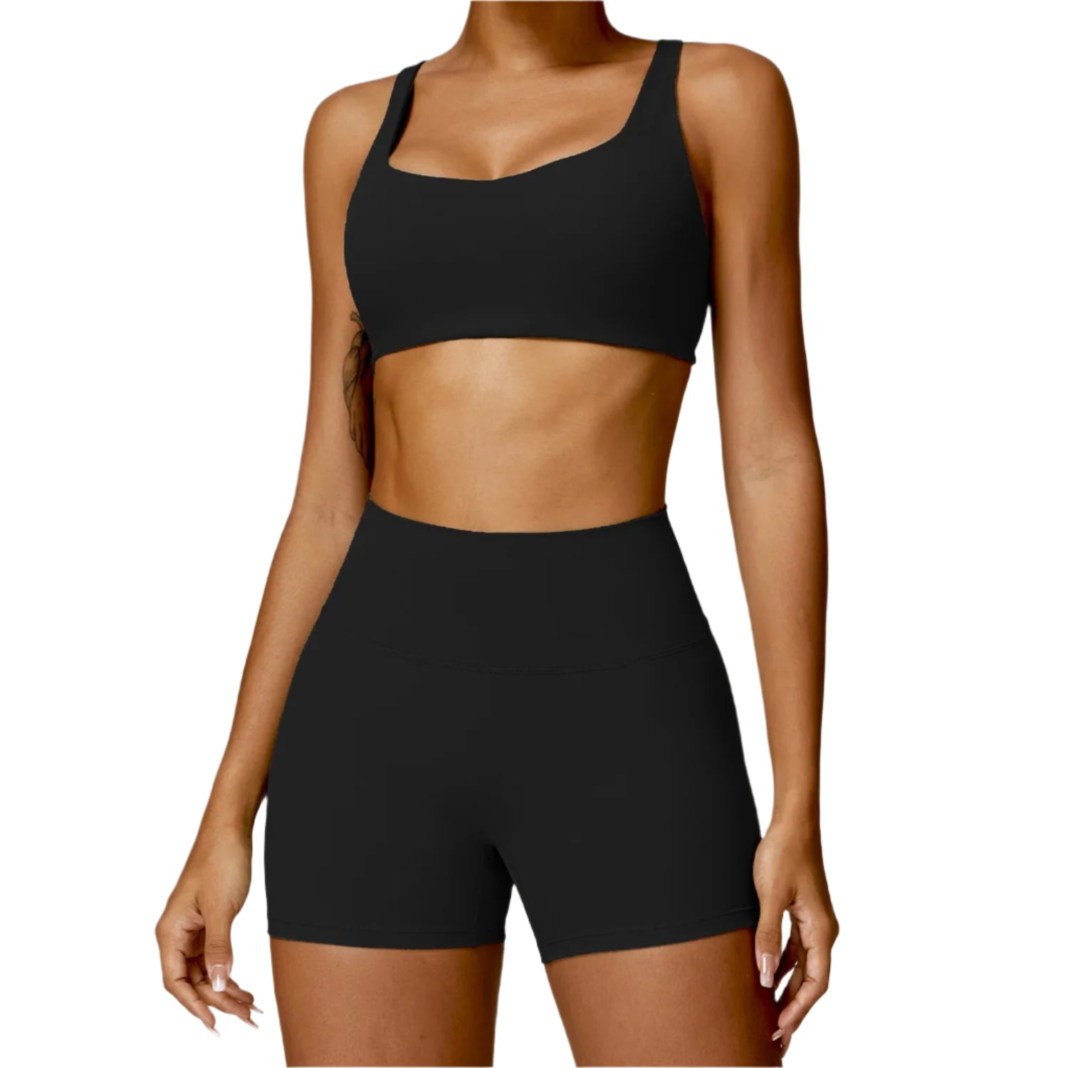 Person wearing a black sports bra and high-waisted shorts on a white background