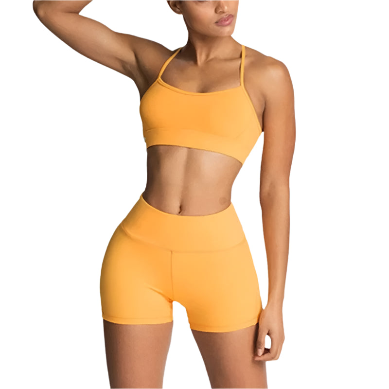 Woman wearing a yellow sports bra and shorts set on a light gray background